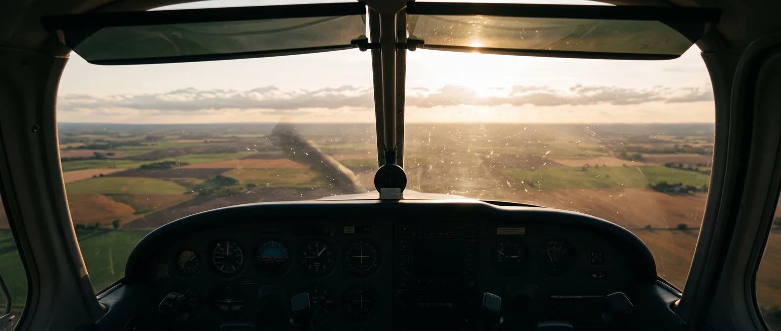 General aviation cockpit view toward the horizon at golden hour (AI-generated)